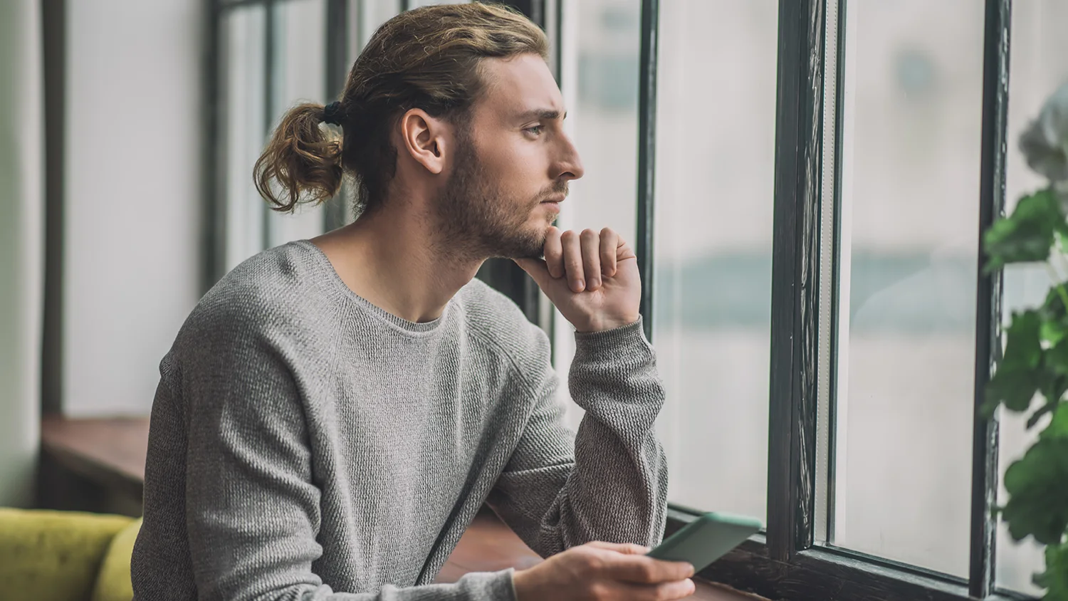 a man looks sadly out a window